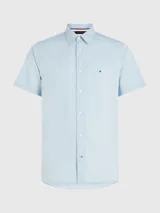 Camisa celeste de mangas cortas, confeccionada en popelín de puro algodón. Tiene cuello abotonado, bajo redondeado y logo de Tommy Hilfiger bordado en el pecho.
