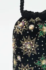 Cartera tipo tote bag de terciopelo negro con bordados de flores y estrellas de lentejuelas y mostacillas de colores. Tiene doble asa de cordón trenzado negro con cuentas en los extremos.