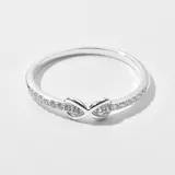 Anillo plateado con forma de infinito y pequeños brillantes incrustados.