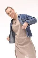 Campera de jean azul con cuello clásico, cierre frontal con botones metálicos, bolsillos con solapa en el pecho y ruedo desflecado.