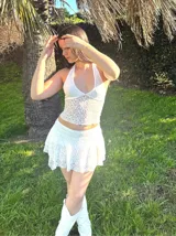 Conjunto de encaje blanco compuesto por un top halter y una minifalda con short incorporado.