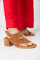 Sandalias de cuero color tostado, con plataforma de 1 cm y taco cuadrado de 6 cm. Presenta tiras cruzadas en el empeine, una tira ancha con abertura en el frente y pulsera con hebilla.
