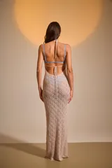 Vestido largo de acrílico color beige, tejido con diseño calado y cuello halter.