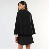 Chaleco tipo capa color negro con cuello redondo y cierre frontal con botones dorados.