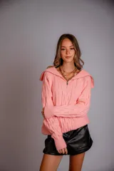 Buzo de punto color rosado, con cuello polo y cierre frontal parcial, de manga larga y diseño holgado.