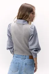 Sweater gris de punto con cuello en V y diseño de trenzas.