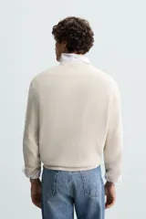 Jersey color crudo tejido en hilatura de algodón, con cuello redondo, manga larga y acabados en rib.