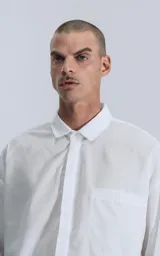 Camisa blanca de manga larga con bolsillo en el pecho, de calce oversize confeccionada en textil fresco y liviano.