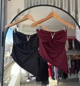 Top bandeau negro con escote asimétrico y detalle de abertura en el abdomen.