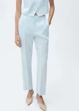 Pantalón de vestir celeste claro de lino, con tiro alto, corte recto, bolsillos laterales y traseros, trabillas y cierre frontal oculto con botón, gancho y cremallera.