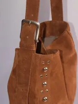 Bolso tipo bandolera de cuero negro con flecos y tachas plateadas. Tiene correa regulable, forro interior y bolsillo interno.