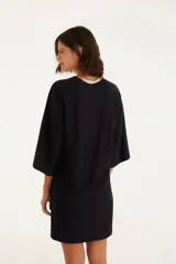 Vestido corto negro con estampado de espirales color crema y naranja, cuello redondo y mangas anchas.