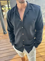 Camisa negra de manga larga con cuello clásico y botones color madera.