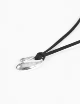 Collar con cordón negro ajustable y dije plateado con forma orgánica.