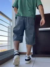 Bermuda de jean gris oscuro con lavado gastado, corte ancho y largo a la rodilla.