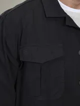 Camisa gruesa de gabardina color azul marino, con cuello clásico, cierre frontal con botones a presión, cuatro bolsillos frontales con solapa y puños abotonados.