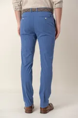 Pantalón de vestir color gris claro, de corte slim fit, con bolsillos laterales y traseros. Se ajusta a la cintura con cinturón de cuero marrón.