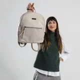 Mochila color marrón claro, combinada con apertura frontal y bolsillo interior. Tiene asa de mano y correas de galón regulables para colgar en la espalda.