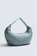 Bolso de hombro acolchado celeste de tejido técnico con cierre de cremallera. Tiene un bolsillo interior con cremallera y asa ajustable.