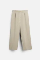 Pantalón color beige de corte ancho, con pliegues frontales, bolsillos laterales y traseros de doble vivo.