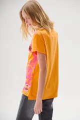 Remera color naranja con estampado floral en tonos rosa y fucsia, con la palabra "LAMODE" en relieve y contorno de labios.