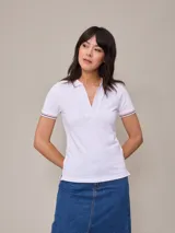 Remera polo blanca de piqué con cuello sin botones y mangas cortas con ribete a rayas rojas y azules. Corte clásico.