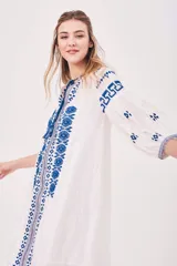 Vestido túnica blanco con bordados azules, mangas 3/4 y cuello con lazo ajustable.