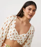 Blusa cropped de lino con escote corazón, lazada en la espalda, manga larga abullonada y estampado de anacardos.
