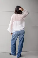 Blusa blanca de gasa con volados en el frente y mangas acampanadas.