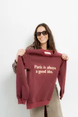 Buzo color borgoña con cuello redondo y mangas largas. Estampa frontal con la frase 'Paris is always a good idea' en color crema.