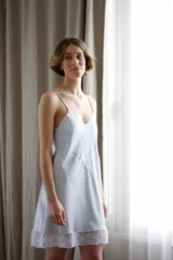 Camisón corto negro de satén con breteles finos y escote en V con puntilla blanca.