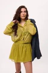 Vestido corto color verde lima, estilo camisero, confeccionado en chiffon transparente. Tiene cuello camisero, mangas largas abullonadas y elástico en la cintura.