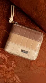 Billetera corta con cierre perimetral, confeccionada en símil cuero con textura croco. Interior con visor, tarjetero, división para billetes y bolsillo monedero con tapa y broche.