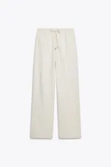 Pantalón de tiro alto color hueso, con bolsillos delanteros y traseros, cintura elástica ajustable con cordones y corte ancho.