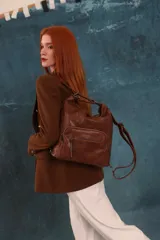 Cartera mochila de cuero sintético color marrón, con compartimento principal amplio y bolsillos frontales con cierre. Tiene correas ajustables y asa superior.