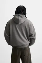 Sudadera con capucha gris confeccionada en tejido de algodón con interior de rizo, manga larga, bolsillo tipo canguro y terminaciones en rib.