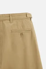 Pantalón chino color beige de corte recto, con cintura ajustable con cordón interior y trabillas laterales. Tiene bolsillos frontales y traseros de vivo.