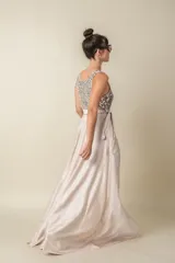 Vestido largo de fiesta color champagne, con corpiño de lentejuelas plateadas, falda de satén liso y lazo de satén en la cintura. Corsé de tul bordado. Talle único adaptable de S a L.