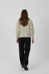 Sweater acrílico color natural, con cuello redondo, diseño de fantasía y corte ajustado al cuerpo. Presenta mangas largas abullonadas con detalles de punto en relieve.