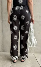 Pantalón negro con estampado de rombos blancos, de corte recto y tiro alto.