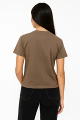 Remera de algodón color crudo con estampado de un labial rojo y texto en color bordó que dice "It's OK to wear lipstick". Corte clásico, cuello redondo y mangas cortas.