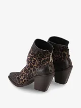 Bota corta de gamuza con estampado de leopardo en tonos marrones y negros. Presenta un taco ancho y alto de color marrón oscuro, punta cuadrada y cierre de cremallera en la parte trasera.