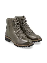 Borcego alpino color verde oliva de cuero napa con detalles metálicos, base de goma estilo trucker con pespuntes naturales en contraste y cordones de algodón al tono. Diseñado en Uruguay y fabricado en Brasil.