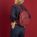 Mochila bordeaux de símil cuero con cierres metálicos, doble bolsillo frontal, asa de mano y correas regulables en galón.