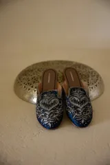 Zuecos azul marino con bordados plateados y suela de cuero.