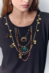 Remera negra de algodón con cuello redondo y mangas cortas. Presenta un estampado en el escote que simula un collar estilo boho con cuentas, borlas y dijes.