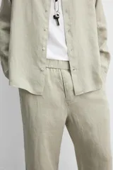 Pantalón negro regular fit confeccionado en tejido de lino. Cintura ajustable con cordón interior, bolsillos frontales y detalle de bolsillos traseros de vivo.