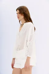 Camisa negra amplia de algodón con escote redondo y abertura corta con botones en el frente. Cuenta con bordados cut-out en el ruedo y mangas largas terminadas en puño con botón.