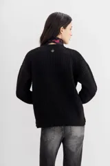 Cardigan negro de tejido de punto con ochos y terminaciones en punto rib. Presenta calce relajado, mangas largas y apliques bordados en piedras y canutillos en la parte superior del frente.