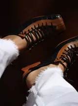 Zapato de diseño artístico, con combinación de piel negra y marrón, de estilo único y tacón bajo.